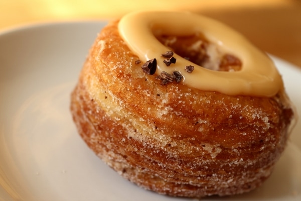 A closeup of a flaky fried doughnut topped with a circle of orange sauce