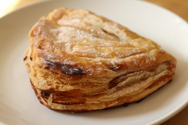 a flaky golden turnover pastry on a white plate