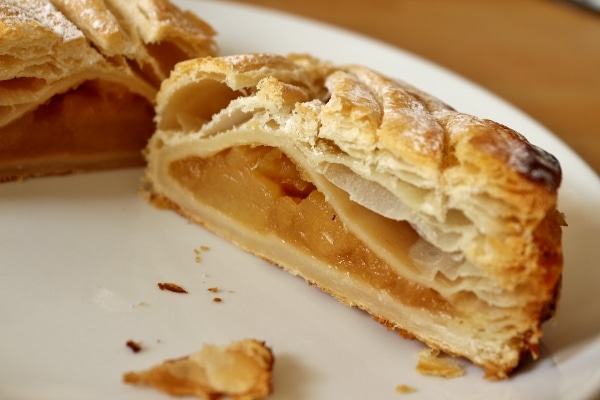 a cross section of an apple turnover on a white plate showing off the filling