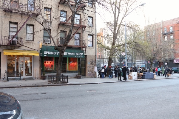 a wide view of a line of people waiting on a city sidewalk