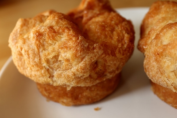 A closeup of a round flaky pastry with a puffy top on a white plate