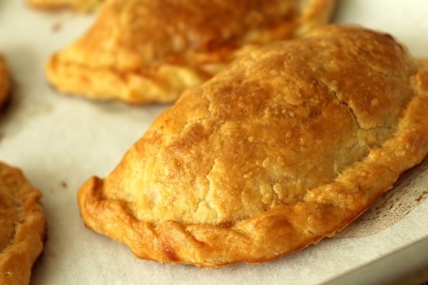 A closeup of a golden brown baked empanada with a crimped edge