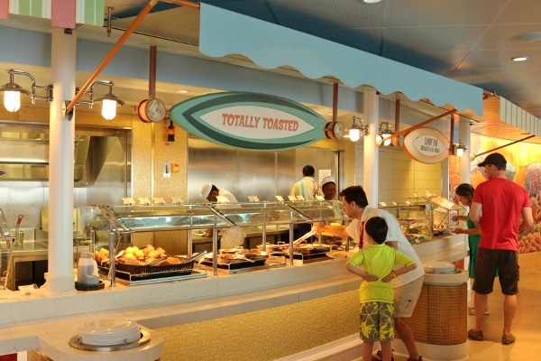 a closeup of a beach themed buffet with a surf board shaped sign hanging overhead