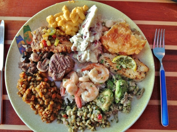 A plate of food including shrimp, fish, and lentils from a buffet