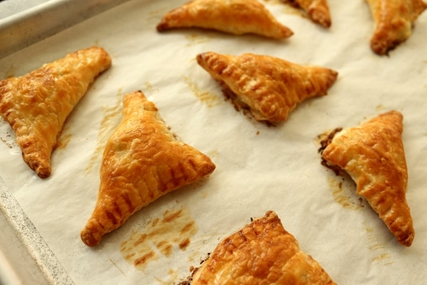 Baked Armenian cheese borek triangles on a baking sheet