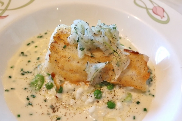 A filet of fish served over risotto with green peas