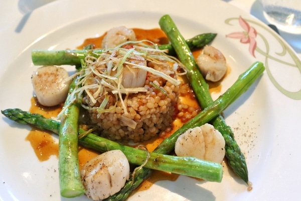 seared scallops arranged around of pile of couscous with green asparagus