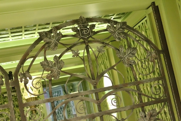 a metal fence with fake leaves on it and pale green decor in the background