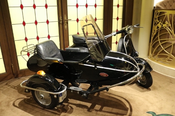 an old-fashioned European looking black motorcycle with a small sidecar attached