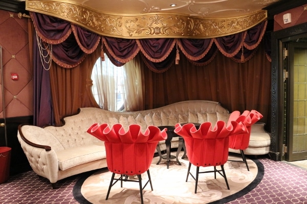 a lounge area with frilly red chairs and a long white couch