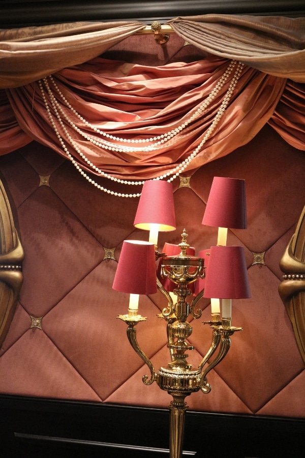 A lamp on a table with a pink tufted wall behind it