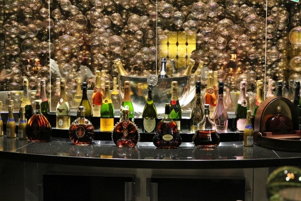 bottles of alcohol on a bar with images of bubbles on the wall behind them