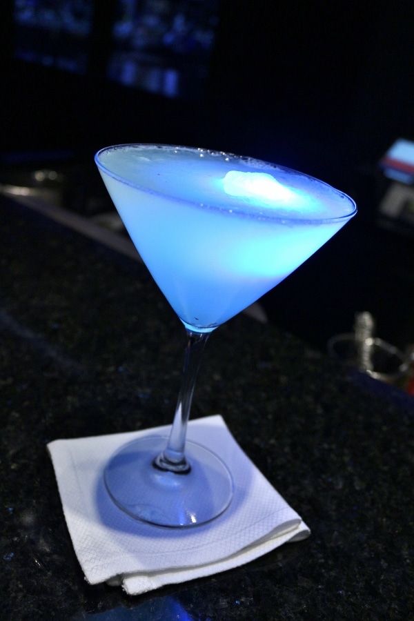 A close up of a cocktail with a glowing cube inside