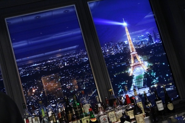 an image of the Eiffel Tower behind a bar stocked with bottles of alcohol