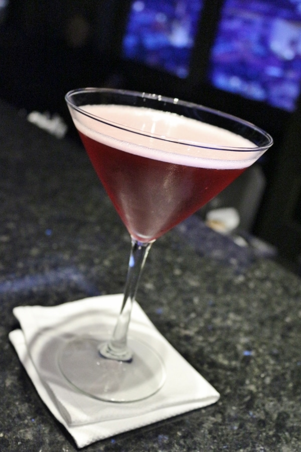 A close up of cocktail glass with a red drink in it