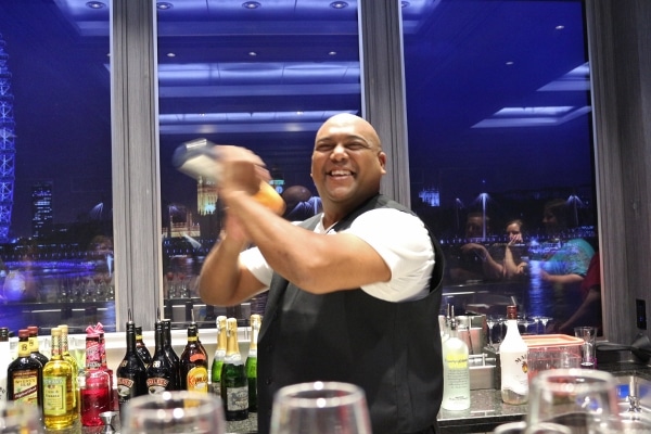 A man behind a bar shaking a drink