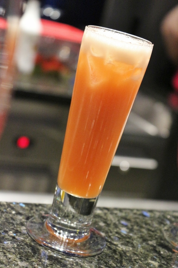 A closeup of a tall glass filled with an orange drink