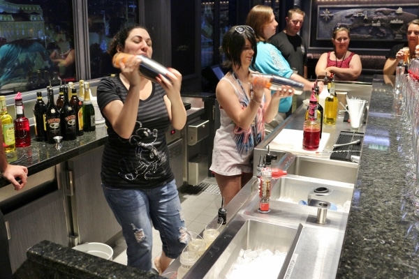 a group of people shaking drinks behind a bar