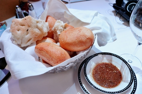 a basket of bread with a dipping sauce in a bowl on the side