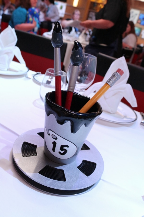 a cup of fake paintbrushes and a pencil with the table number 15 written on it