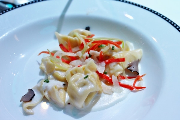 A plate of tortellini pasta in a cream sauce with strips of red pepper