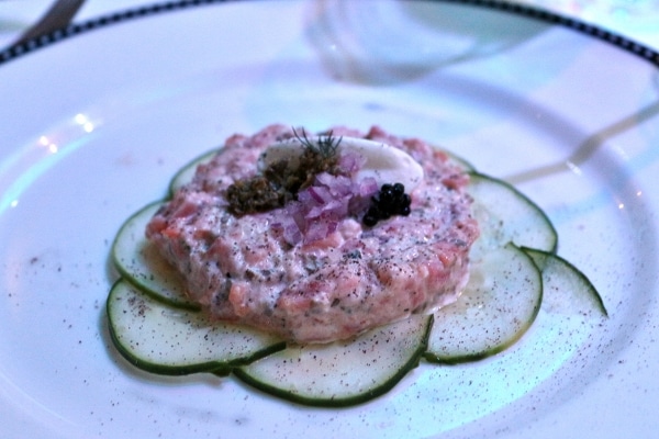 A plate of salmon tartare with cucumber slices and a dollop of black caviar on top