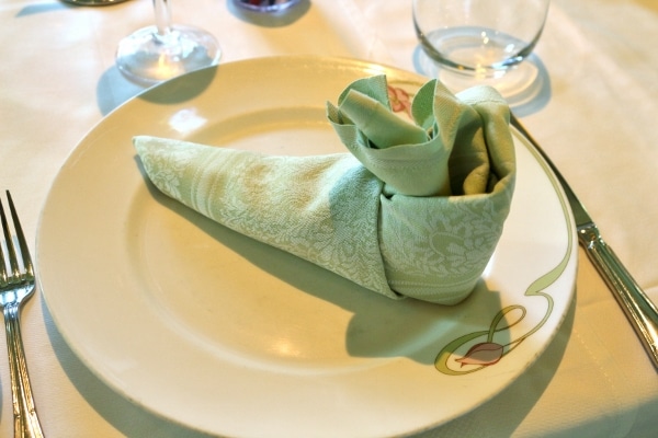 a green cloth napkin folded to look like Peter Pan\'s shoe