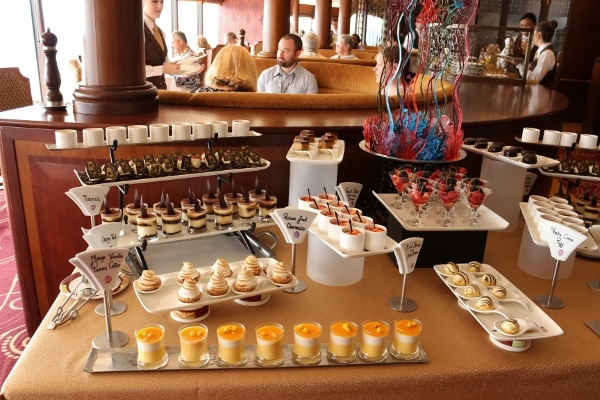 a dessert buffet with small dishes and jars of various desserts