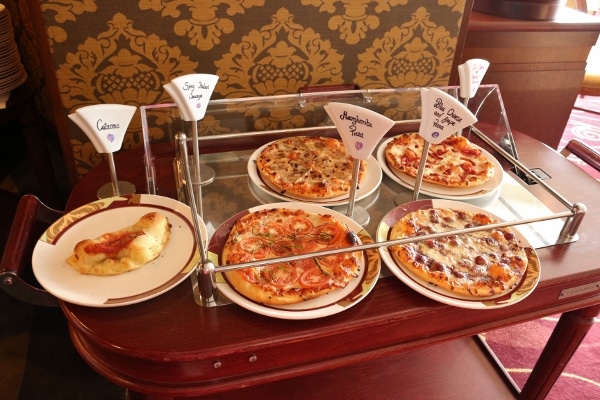 plates of pizzas on top of a rolling cart