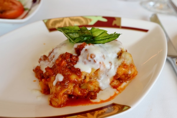 a plate of lasagna with red meat sauce and white sauce poured on top