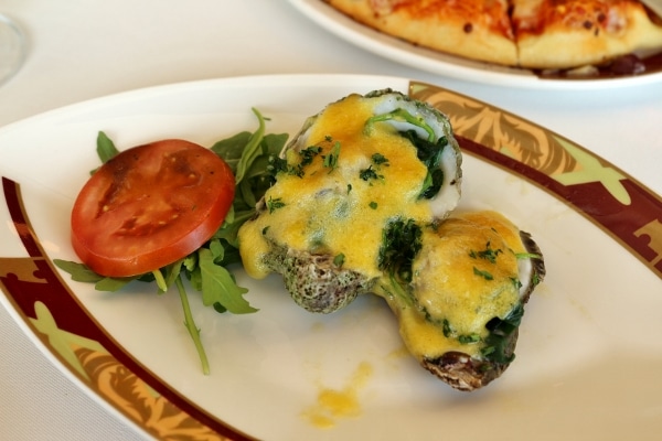 two oysters rockefeller with broiled hollandaise sauce on top served on a plate