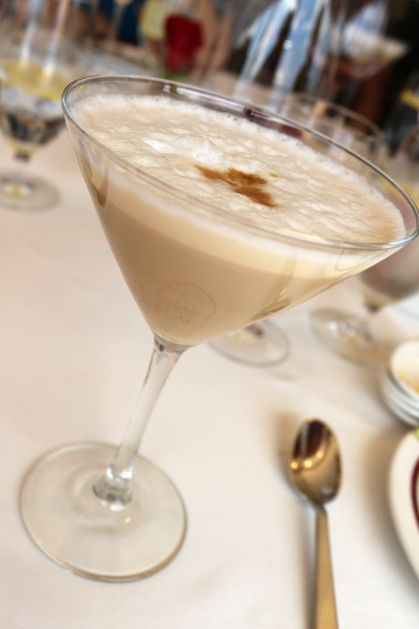 a cocktail glass with a foamy cocktail on a table