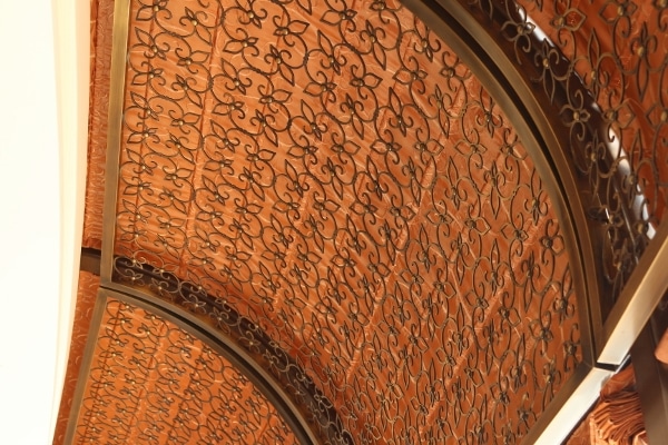 a wrought iron decoration over a curved pink ceiling
