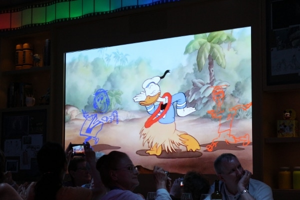 animated line drawings on a screen with Donald Duck wearing a grass skirt