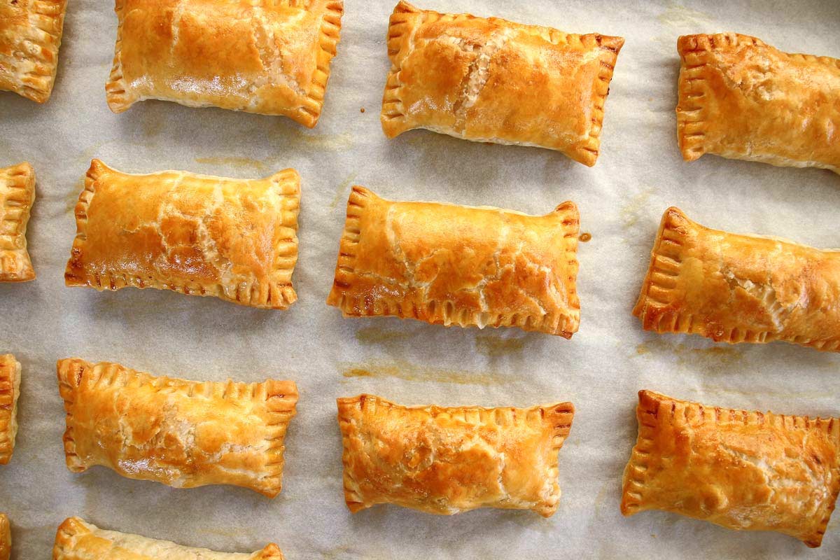 Rectangular golden puff pastry meat boreks on a baking sheet.