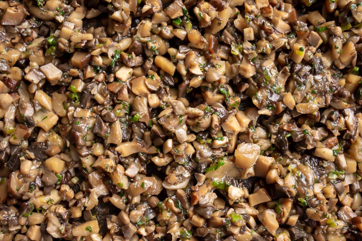 Closeup of cooked chopped mushrooms with herbs.