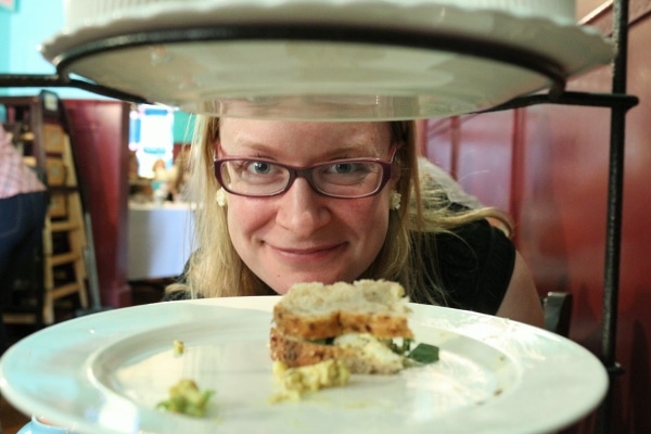 A woman looking at the camera in between tiered plates of food