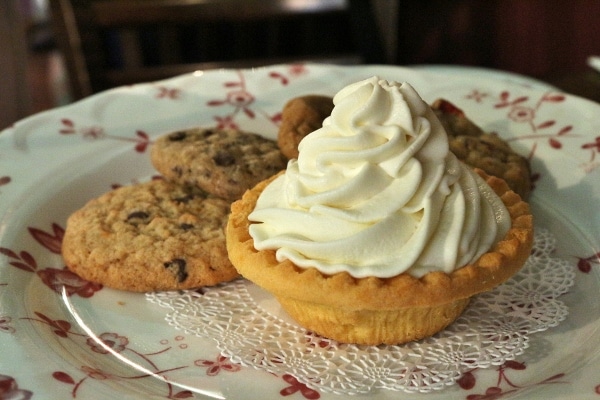 a plate of cookies and a small cream topped tart