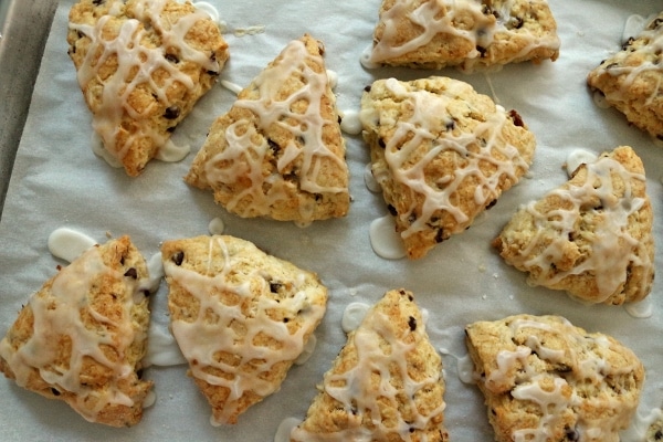 overhead view of triangular scones with glaze drizzled on top on a baking sheet