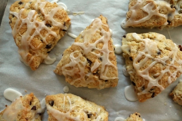 overhead closeup of triangular glazed scones on a parchment paper lined baking sheet