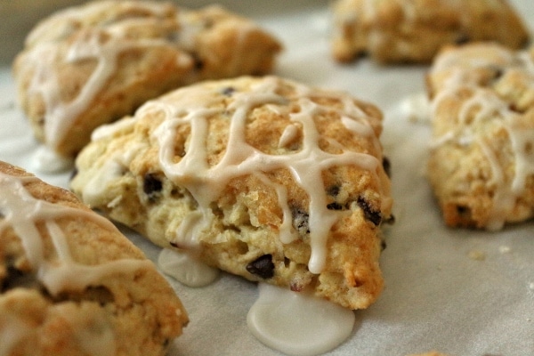 A closeup of a triangular almond joy scone topped with drizzled glaze