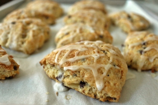 A closeup of a triangular scone topped with drizzled glaze