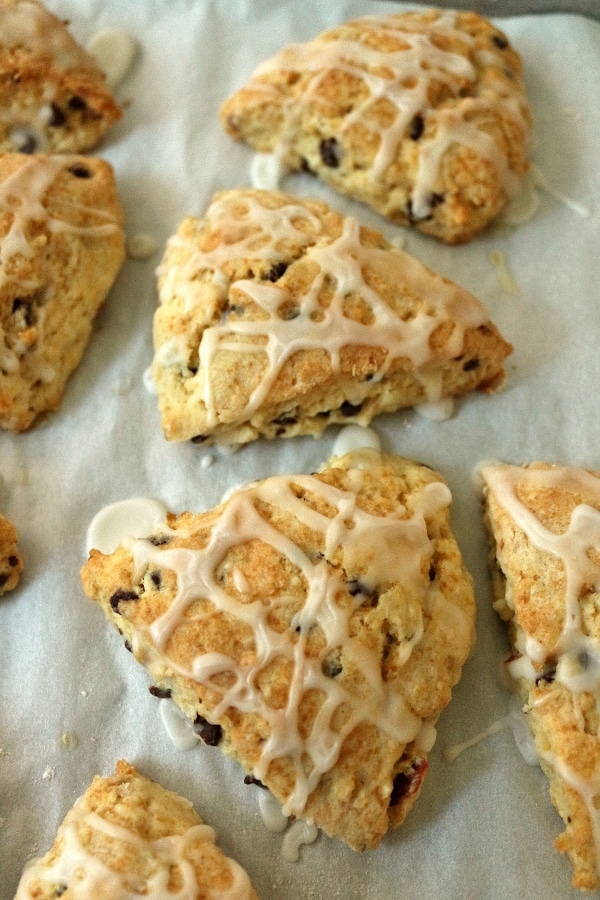 triangular scones topped with drizzled glaze on a parchment paper lined baking sheet