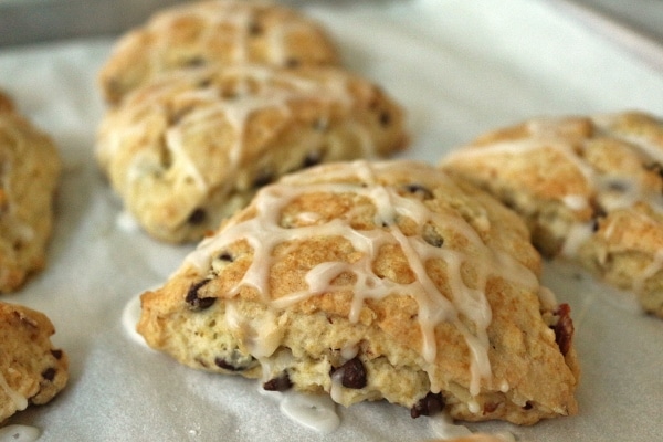 A closeup of a scone with chocolate chips topped with drizzled glaze