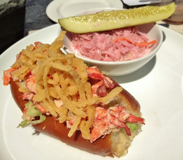 a lobster roll on a hot dog bun topped with fried onion strings