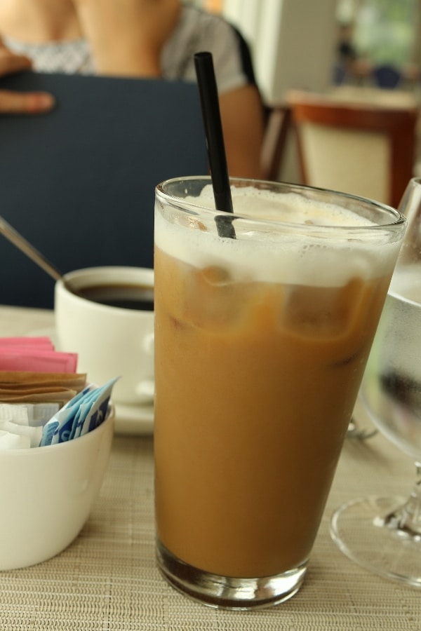 an iced latte in a tall glass on a table