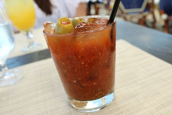 a bloody mary with a green olive garnish in a short glass with a black straw