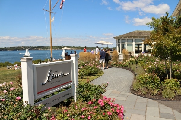 A sign that says The Lawn at Castle Hill with gardens and the ocean beyond