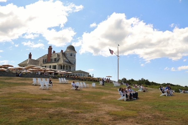 view looking up a field with Adirondack chairs toward a seaside inn