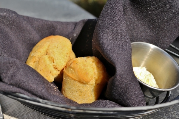 two corn muffins in a bread basket with a black cloth napkin